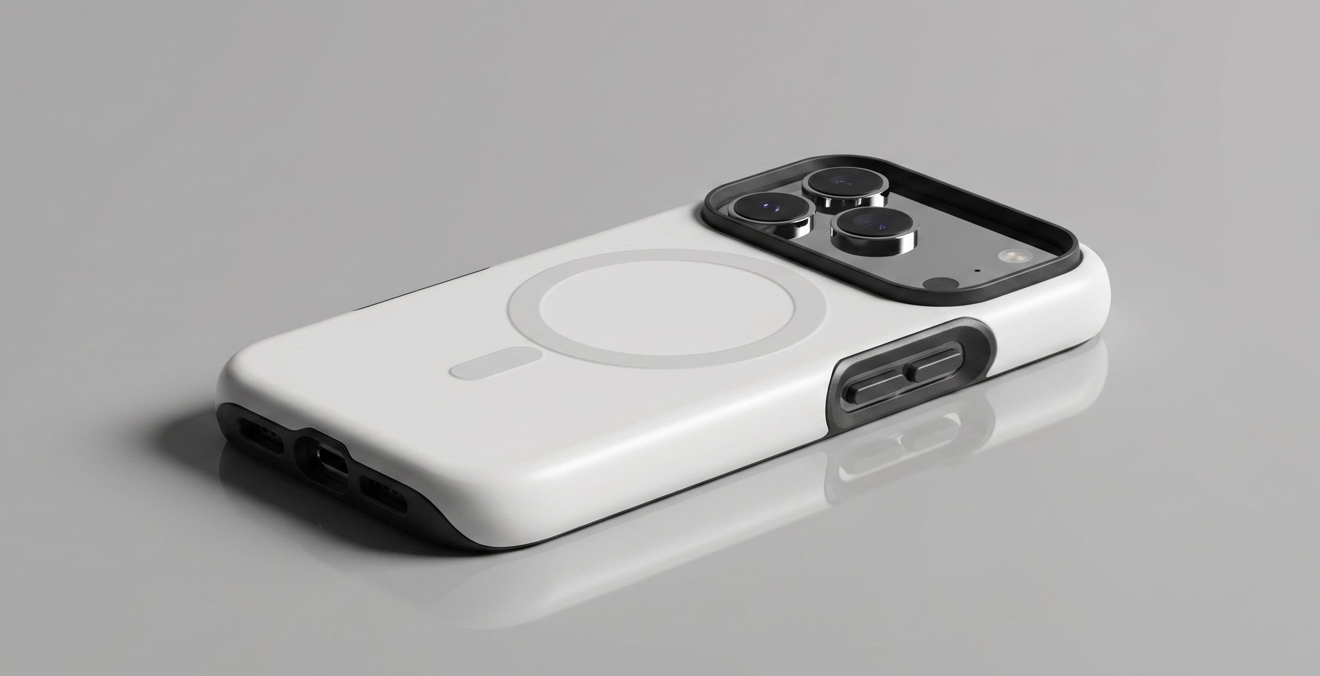 A white MagSafe-compatible phone case with a black camera bumper and side button cover, shown on a reflective gray surface.